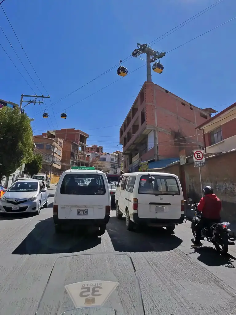 Urban traffic with motorcycles, cars, and a cable car in the streets of La Paz during a motorcycle trip through Bolivia.