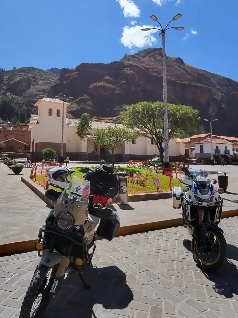 Colonial square with mountains in the background and two parked bikes during a motorcycle trip through the Andes.