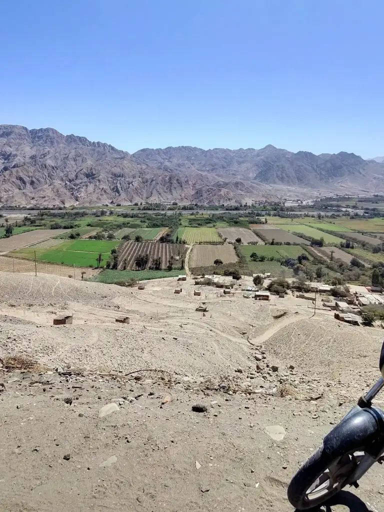 Panoramic view of a farming valley and arid mountains captured on a motorcycle trip.